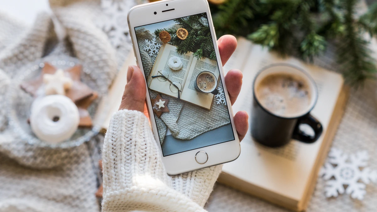 A cosy reading setup with a phone, book, coffee, and glasses